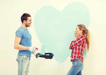 Image showing smiling couple painting big heart on wall