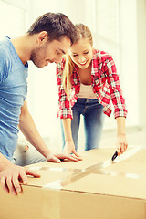 Image showing smiling couple opening big cardboard box