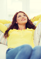 Image showing smiling young woman lying on sofa at home