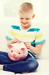 Image showing smiling little boy with piggy bank and money