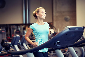 Image showing smiling woman exercising on treadmill in gym