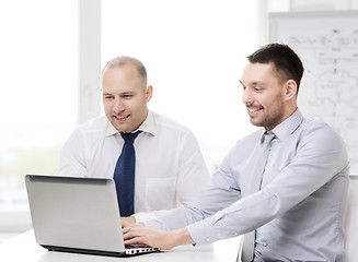 Image showing two smiling businessmen with laptop in office