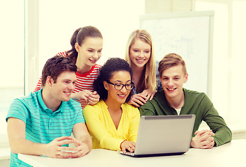 Image showing smiling students looking at laptop at school