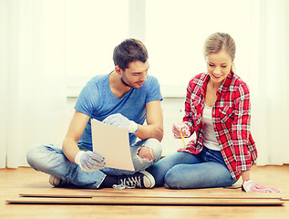 Image showing smiling couple measuring wood flooring