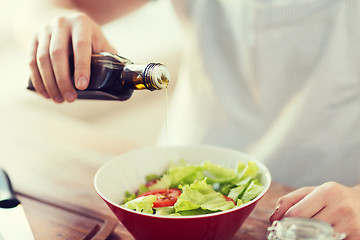 Image showing close up of male hands flavouring salad in a bowl