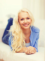 Image showing smiling young woman lying on sofa at home