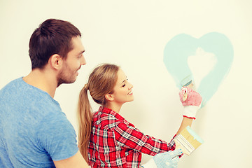 Image showing smiling couple painting small heart on wall