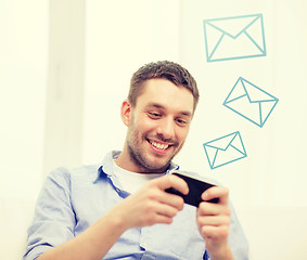 Image showing smiling man with smartphone at home