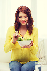 Image showing smiling young woman with green salad at home