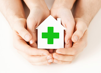 Image showing hands holding paper house with green cross