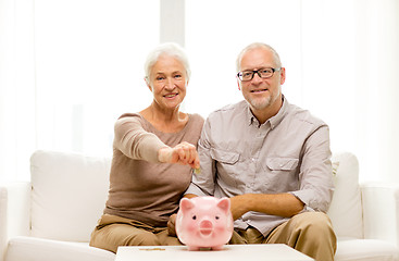 Image showing senior couple with money and piggy bank at home