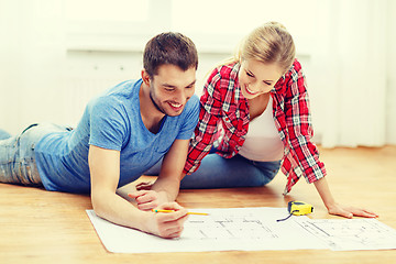 Image showing smiling couple looking at blueprint at home