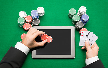 Image showing casino poker player with cards, tablet and chips