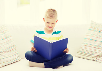 Image showing smiling little boy reading book on couch