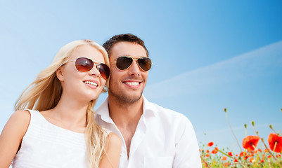 Image showing happy couple in shades over poppy field background