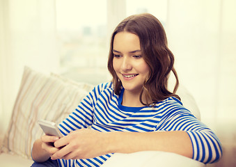 Image showing smiling teenage girl with smartphone at home