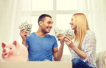 Image showing couple with money and piggybank ot table at home