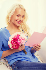 Image showing smiling woman with card and bouquet of flowers