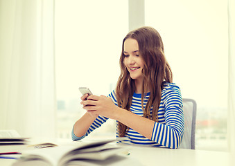 Image showing smiling student girl with smartphone and books