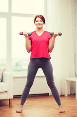 Image showing smiling teenage girl exercising with dumbbells
