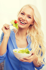 Image showing smiling young woman with green salad at home