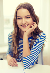 Image showing smiling teenage girl with notebook at home