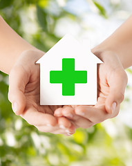 Image showing hands holding paper house with green cross