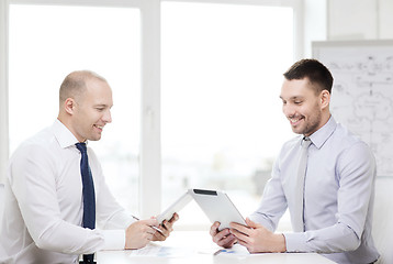 Image showing two smiling businessmen with tablet pc in office