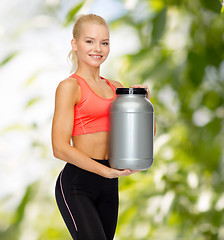 Image showing smiling sporty woman with jar of protein