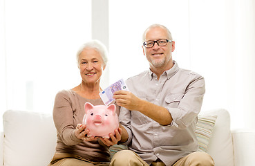 Image showing senior couple with money and piggy bank at home