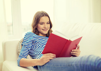 Image showing smiling teenage girl reading book on couch