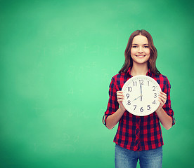 Image showing young woman in casual clothes with wall clock