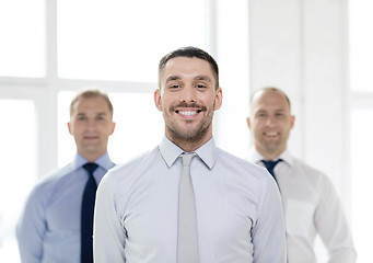 Image showing smiling businessman in office with team on back