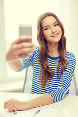 Image showing smiling student girl with smartphone and books