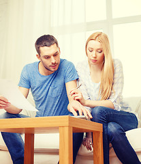 Image showing busy couple with papers and calculator at home