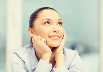 Image showing smiling businesswoman dreaming in office