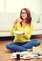 Image showing student eating hamburger and doing homework