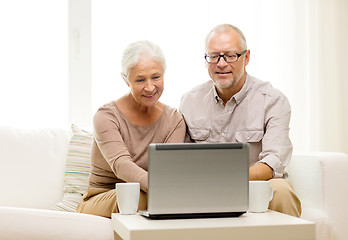 Image showing happy senior couple with laptop and cups at home