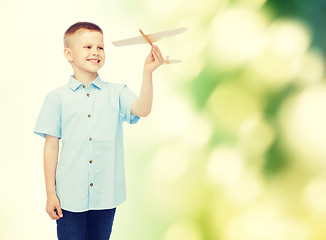 Image showing smiling little boy holding a wooden airplane model