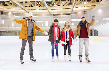 Image showing happy friends waving hands on skating rink