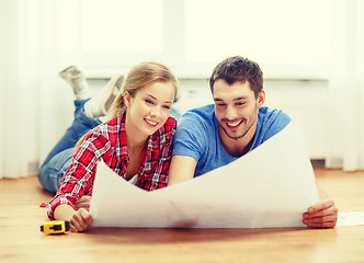 Image showing smiling couple looking at blueprint at home