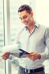 Image showing smiling businessman with clipboard in office