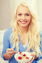 Image showing smiling woman with bowl of muesli having breakfast