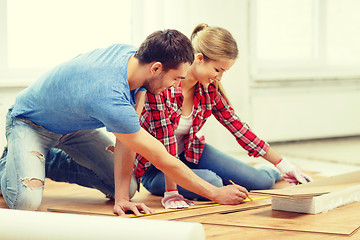 Image showing smiling couple measuring wood flooring