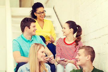 Image showing smiling students with smartphone having discussion