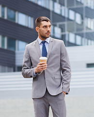 Image showing young serious businessman with paper cup outdoors