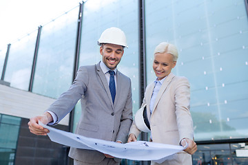 Image showing smiling businessmen with blueprint and helmets