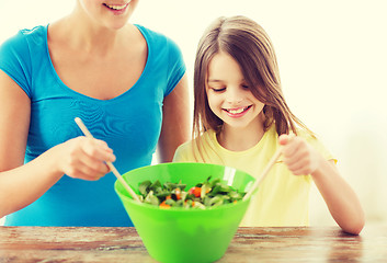 Image showing little girl with mother mixing salad in kitchen