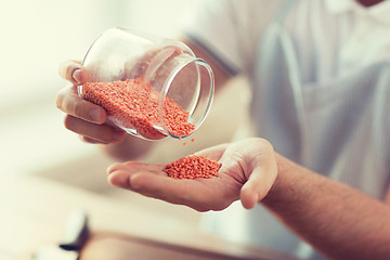 Image showing close up of male emptying jar with red lentils