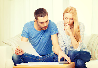 Image showing busy couple with papers and calculator at home